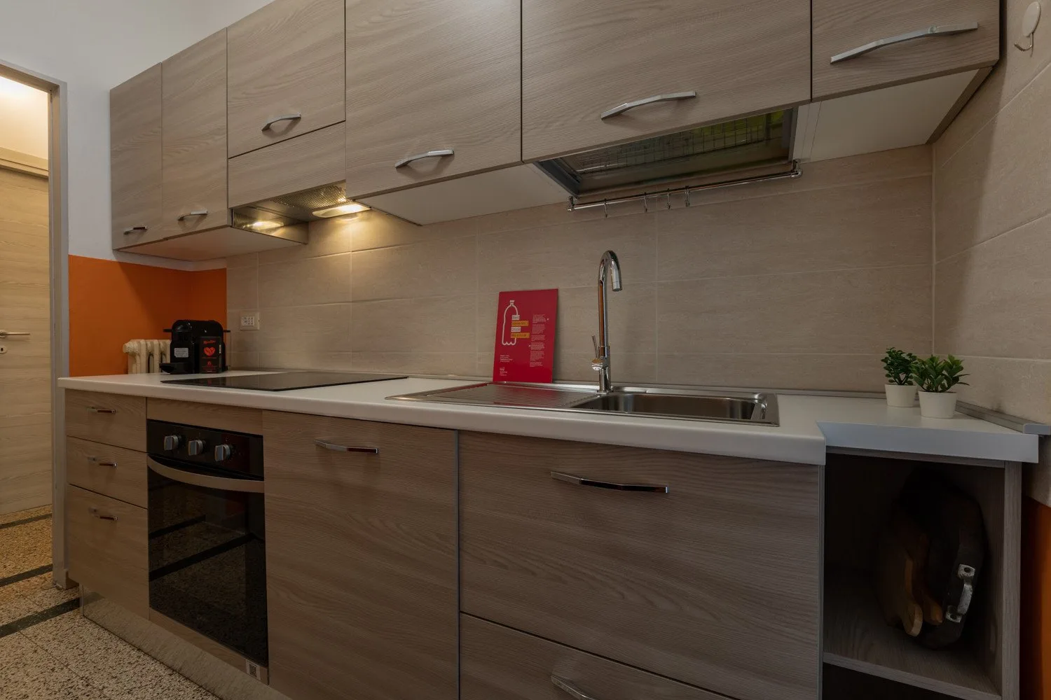 Una cocina compacta con gabinetes de tonos madera, una encimera y un fregadero.