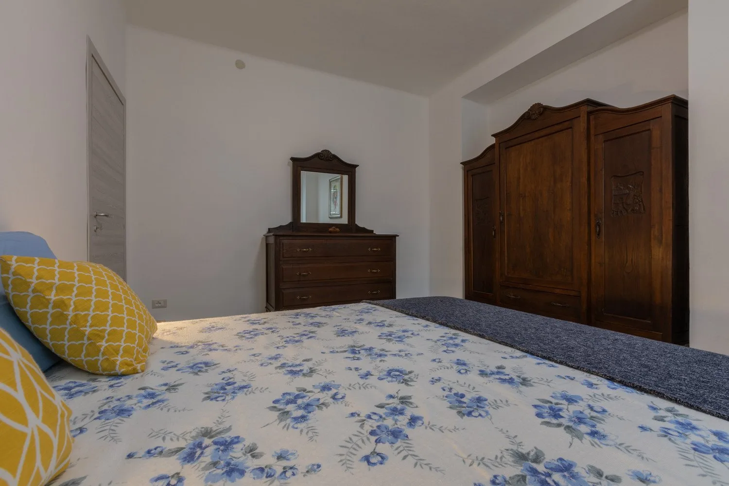 Un dormitorio con una colcha floral y un armario de madera.