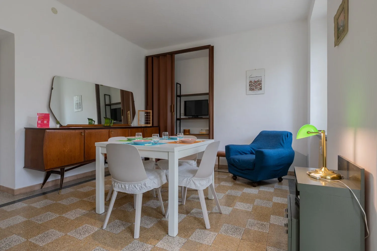 Comedor con una mesa blanca y sillas junto a un sillón azul.