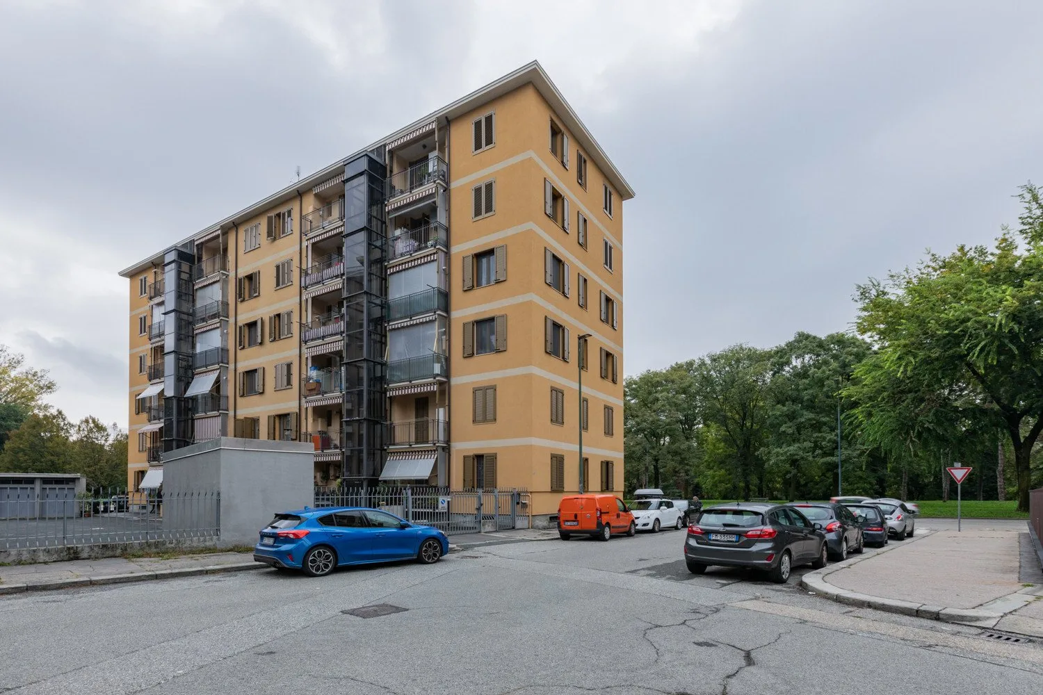 Un edificio de apartamentos de varias plantas se alza junto a un área de estacionamiento con varios autos.