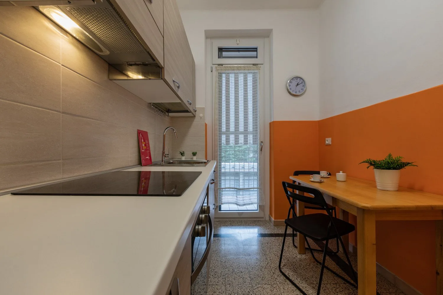 Una cocina compacta con encimera, superficie de cocción y una pequeña mesa de comedor.