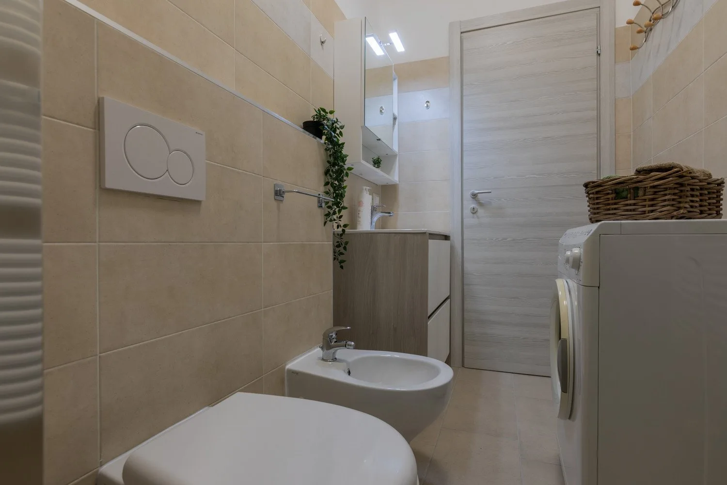 Un baño con azulejos, lavabo, inodoro y una puerta de madera.