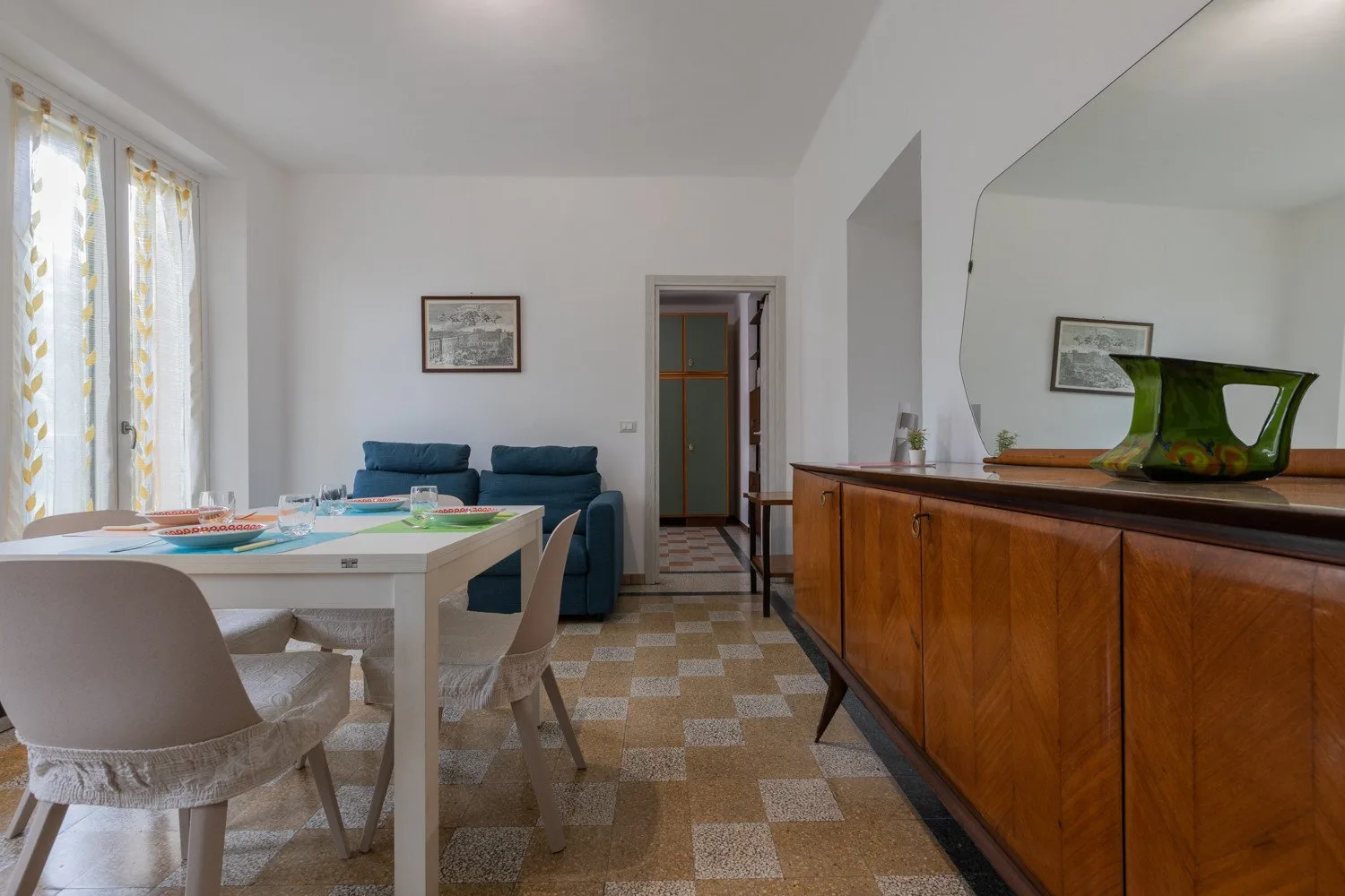 Un comedor luminoso con una mesa, asientos y un aparador de madera.