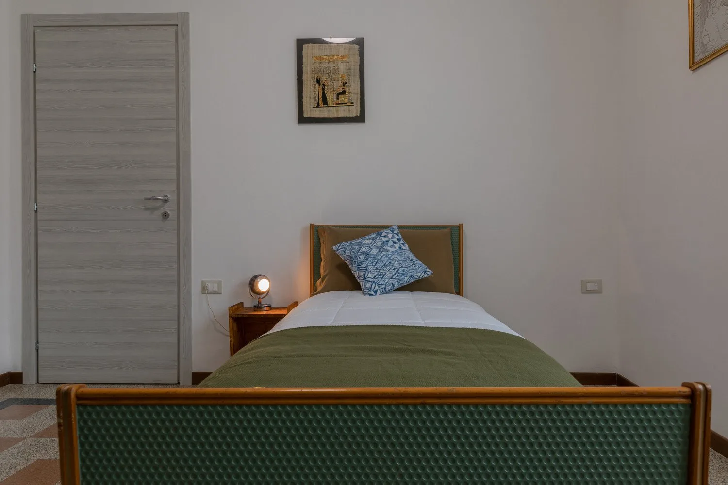 Un dormitorio con una cama, ropa de cama verde y una mesita de noche.