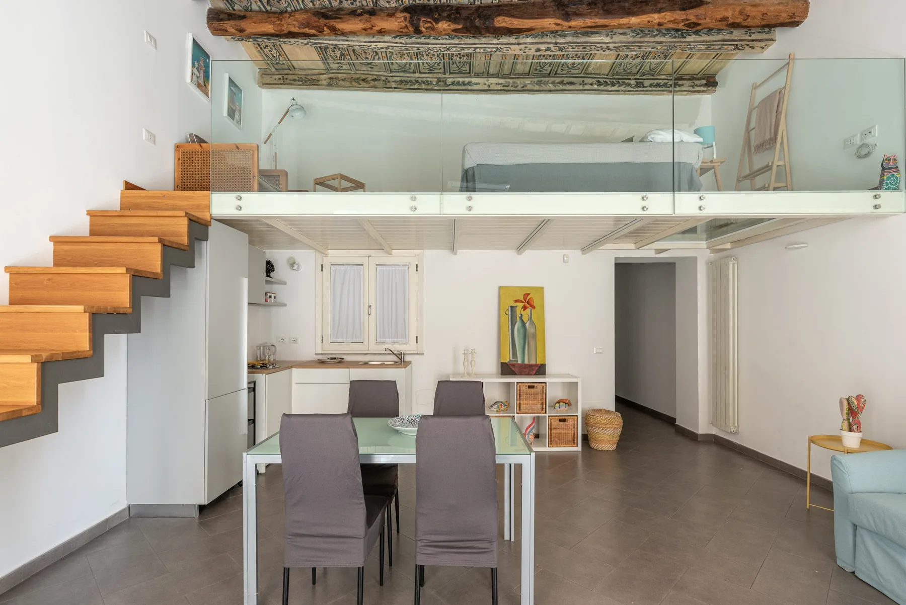 Un salón-comedor diáfano y luminoso con una escalera y un altillo encima.