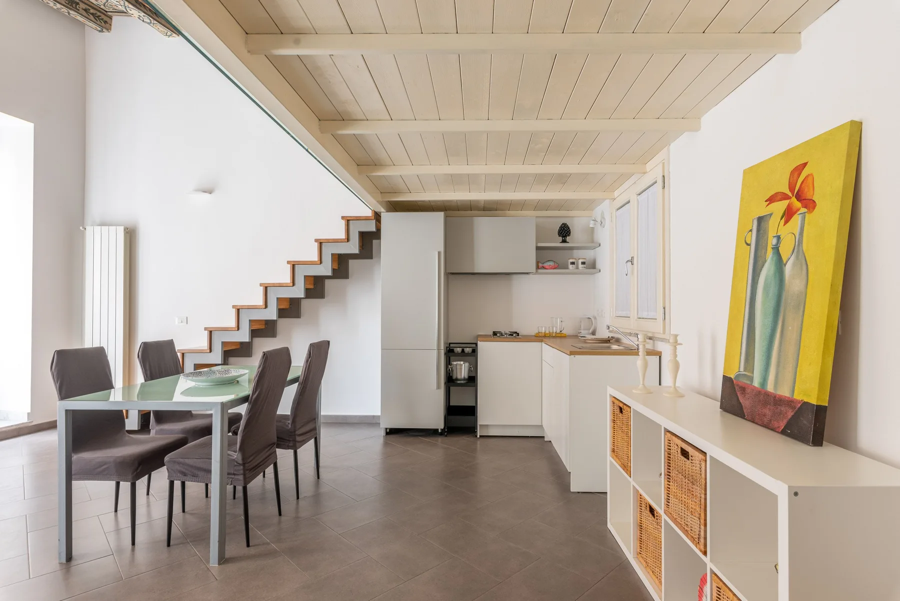 Una luminosa sala de estar con cocina abierta, mesa de comedor y escalera.