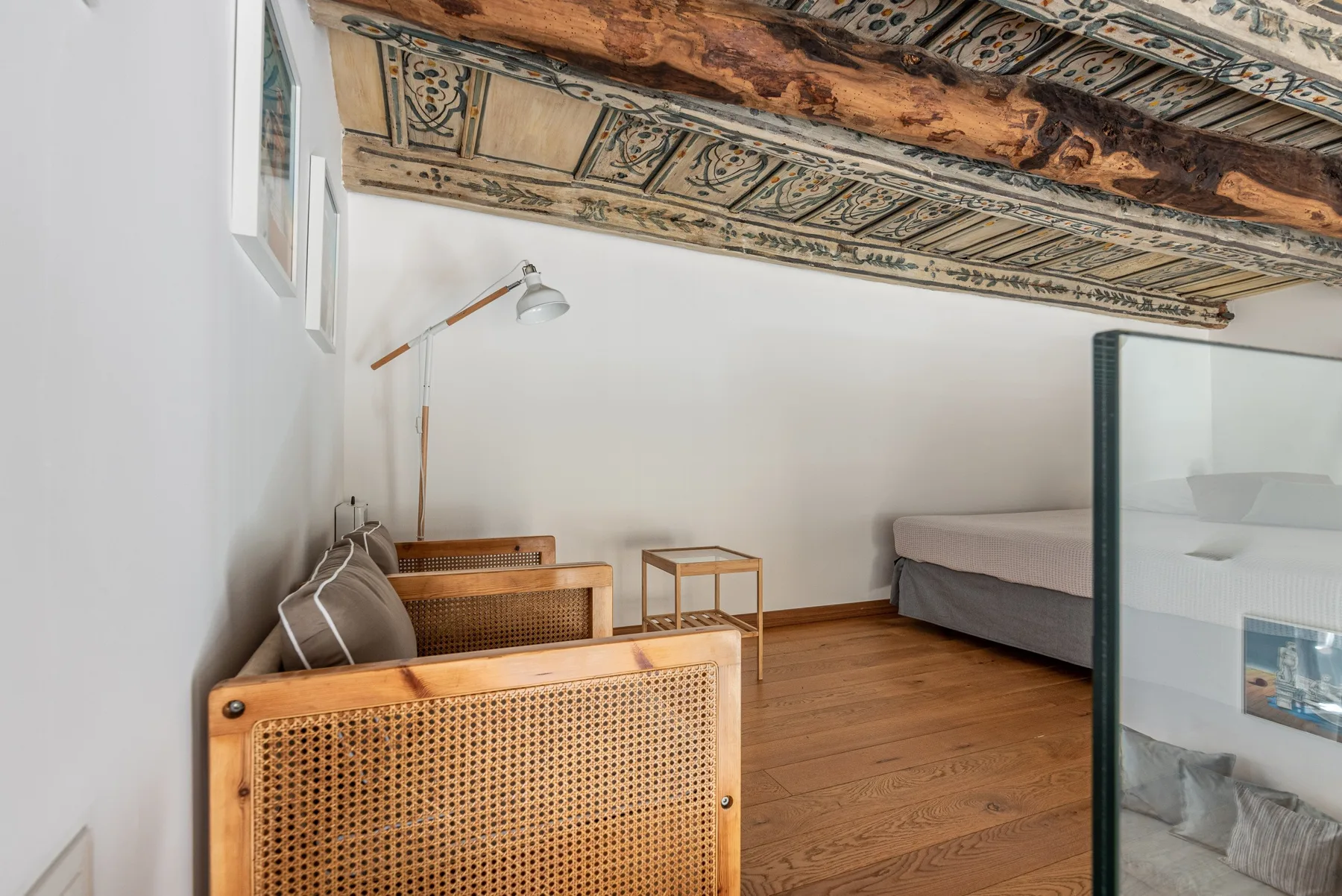 Un dormitorio con una cama, asientos y un techo pintado ornamentado.
