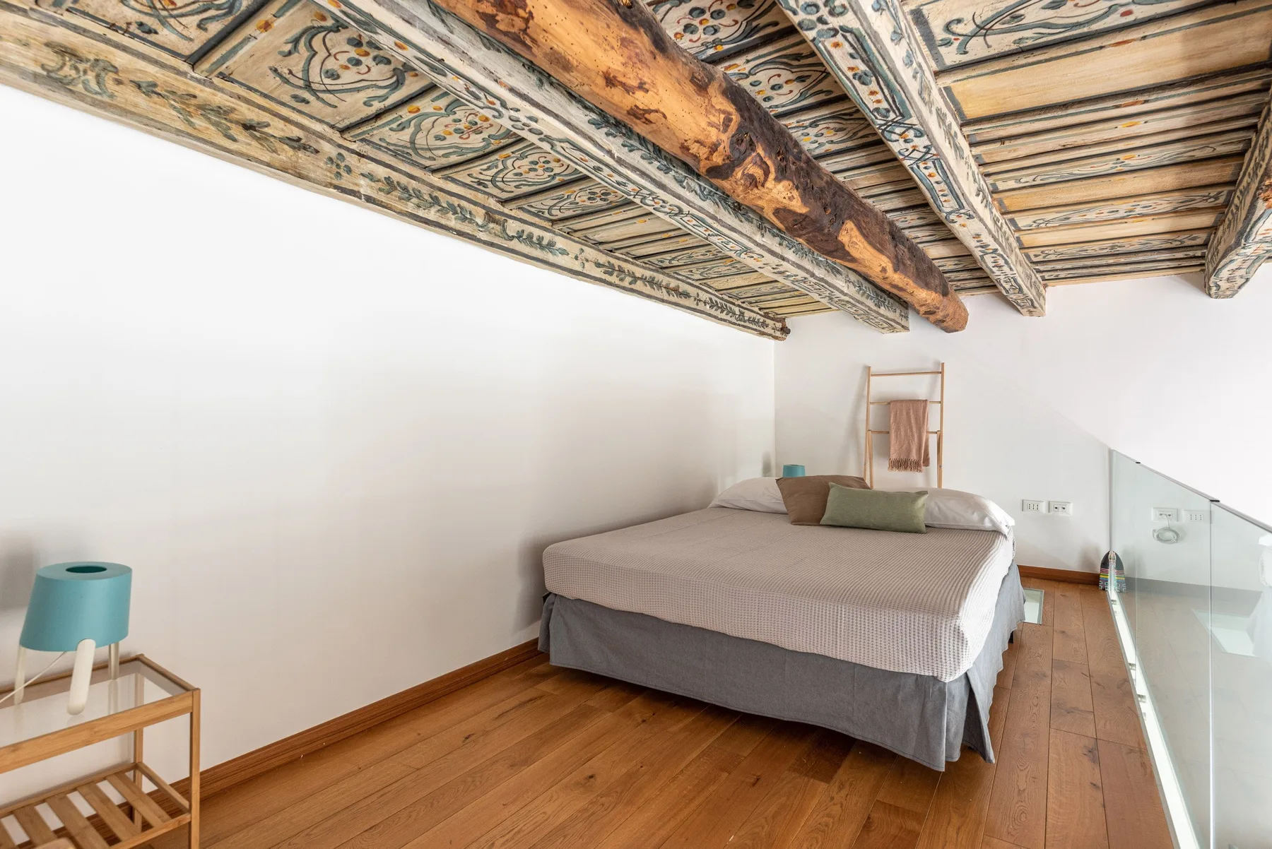 Un dormitorio con una cama bajo un techo pintado decorativo.