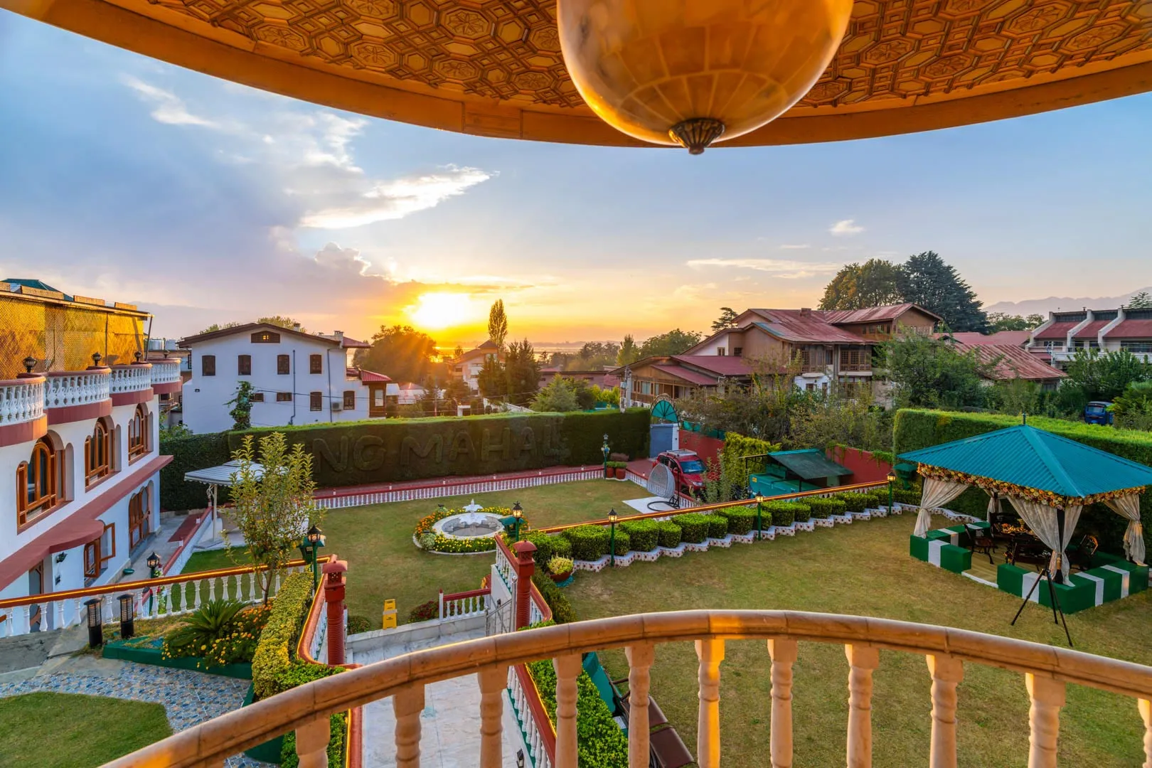 A landscaped garden with seating and play equipment is seen at sunset.