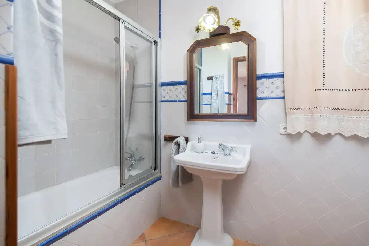 Un baño con bañera, lavabo de pedestal y espejo de pared.
