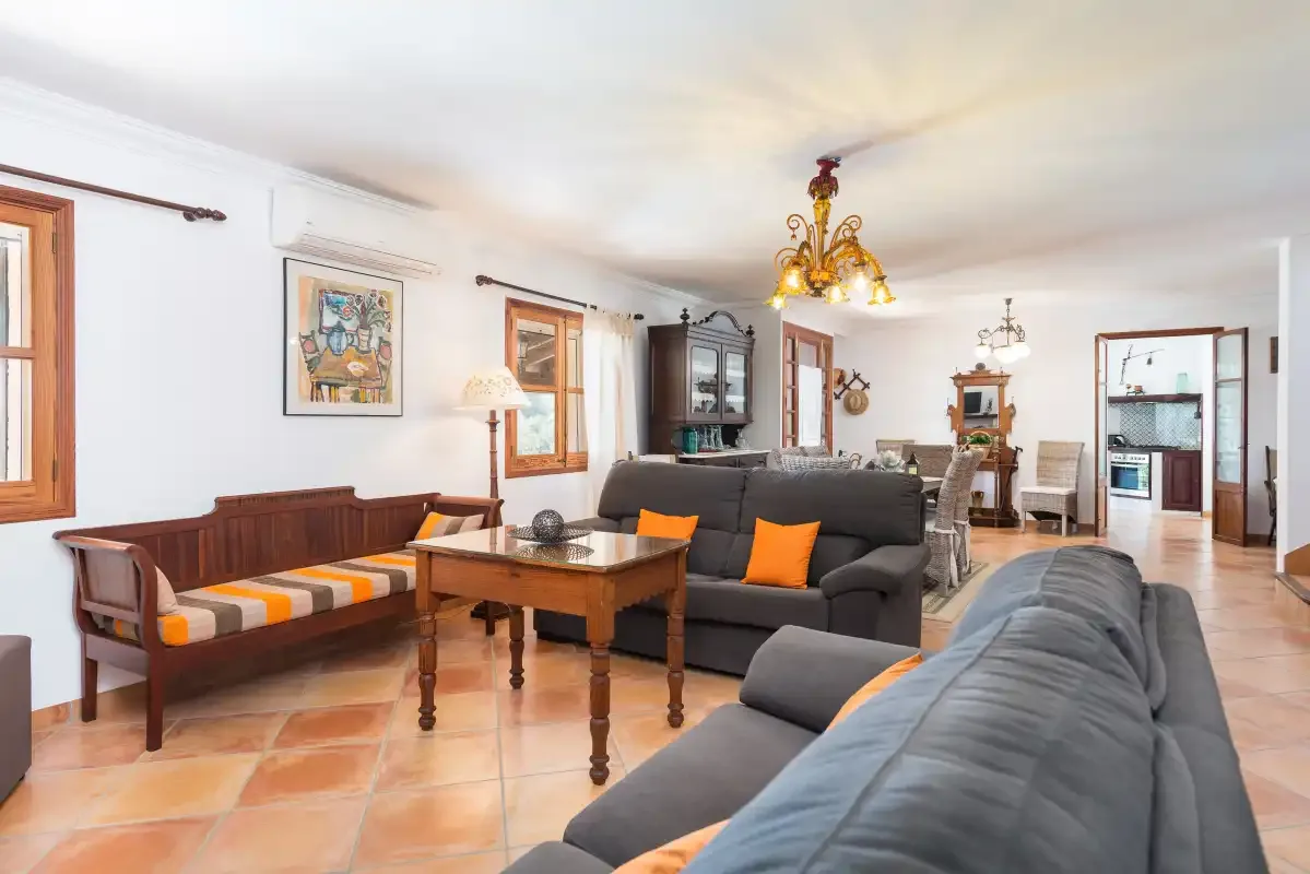Una sala de estar amplia con asientos, una mesa de madera y suelo de baldosas.