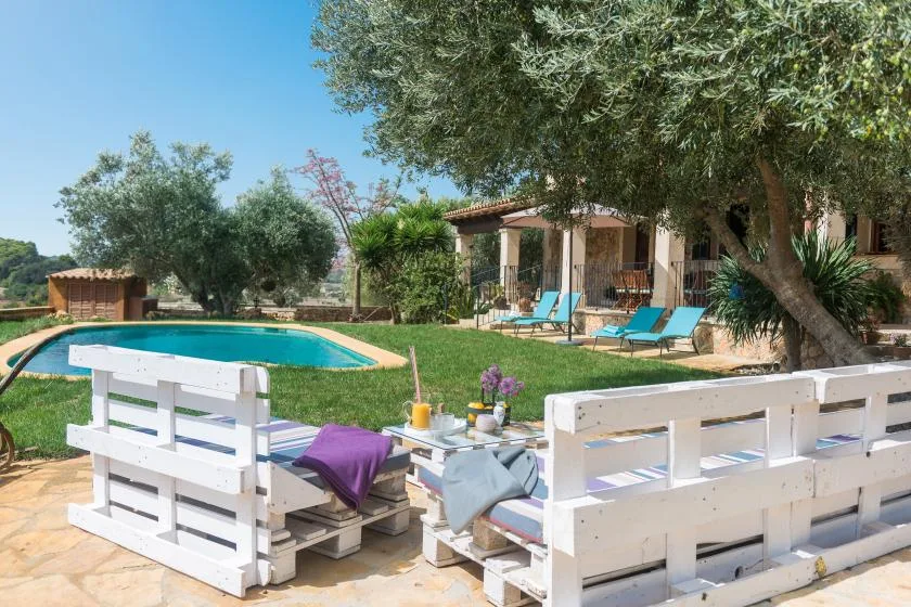 Una zona de piscina al aire libre con asientos y un patio sombreado.