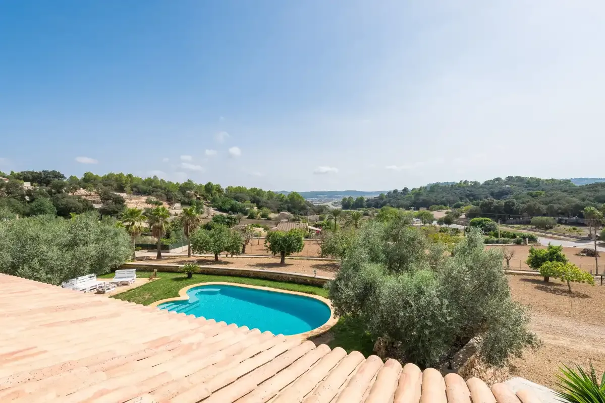 Una piscina está en un entorno rural ajardinado bajo un cielo despejado.
