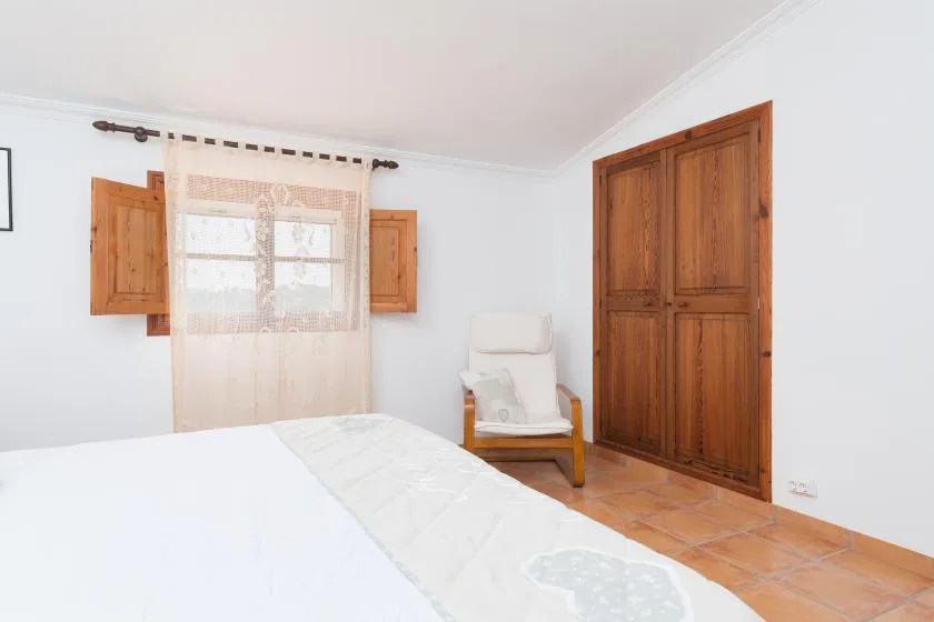 Un dormitorio con una cama, una ventana con cortinas y puertas de madera.
