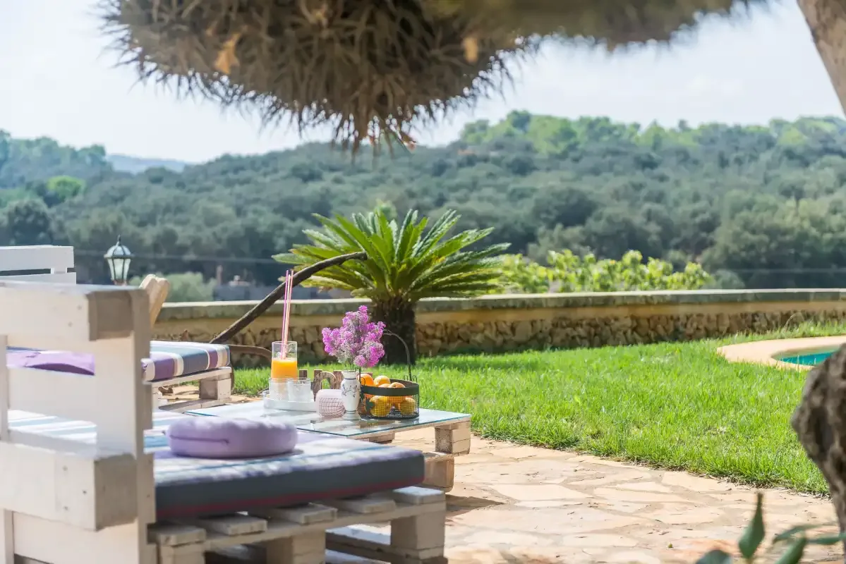 Un patio de jardín con asientos al aire libre da a un césped y colinas boscosas.