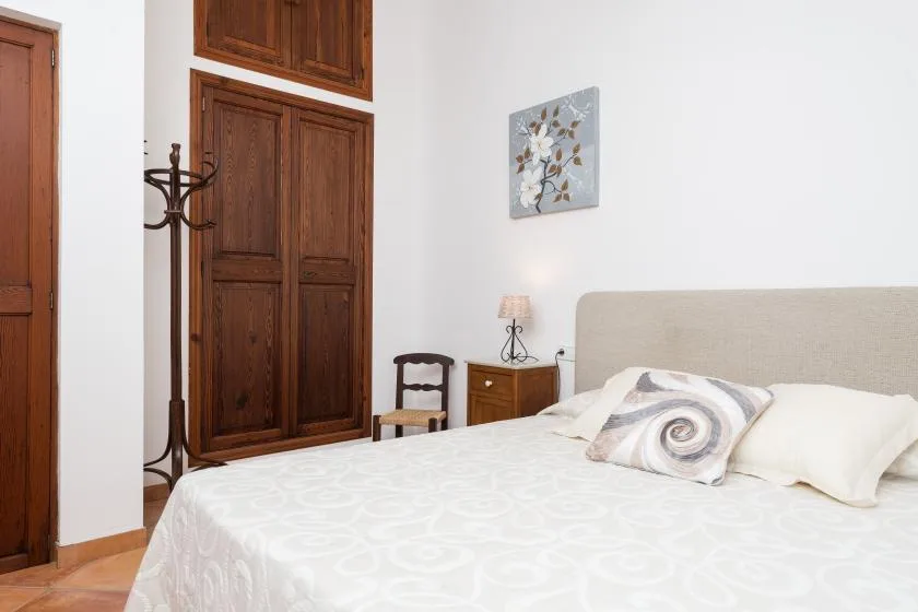 Un dormitorio con una cama bien arreglada y un armario de madera.