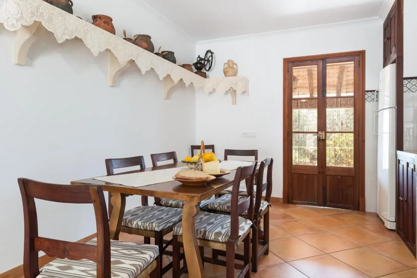 Un comedor con una mesa y sillas de madera junto a una puerta acristalada.