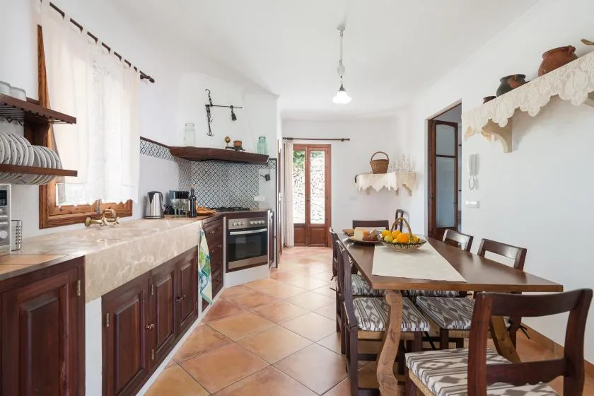 Una cocina-comedor luminosa con una mesa larga de madera y un salpicadero estampado.