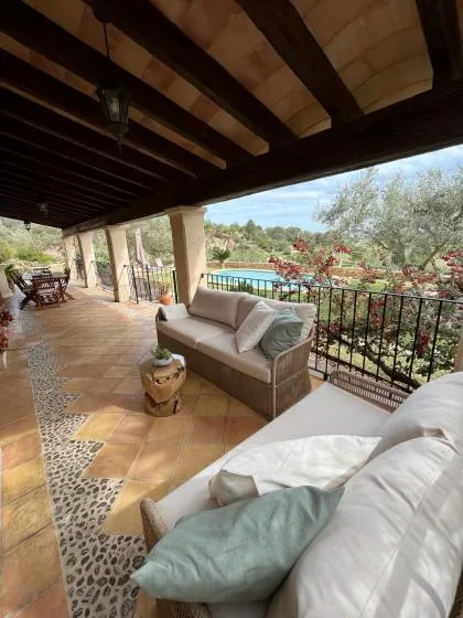 Un patio cubierto tiene asientos acolchados y vistas al jardín y la piscina.
