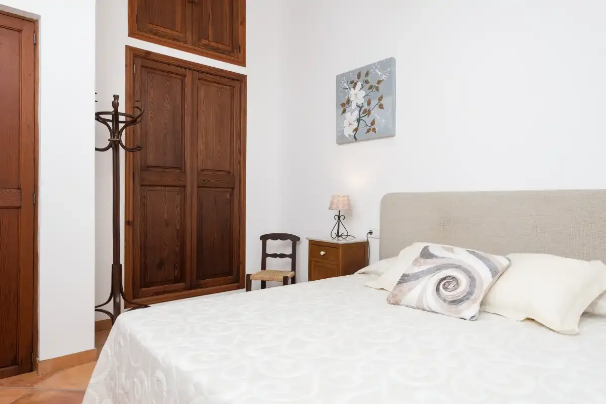 Un dormitorio con una cama, armarios de madera y una mesita de noche.