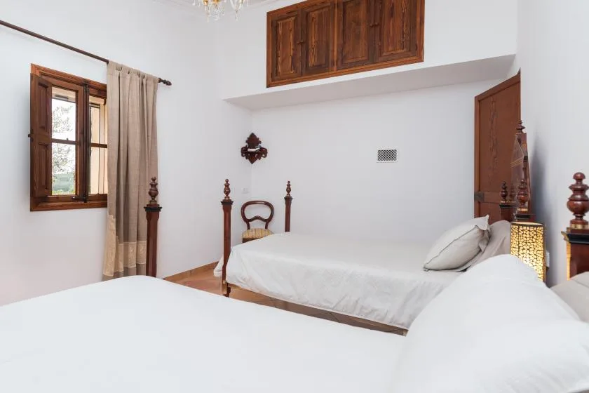 Un dormitorio luminoso con ropa de cama blanca y una ventana con marco de madera.
