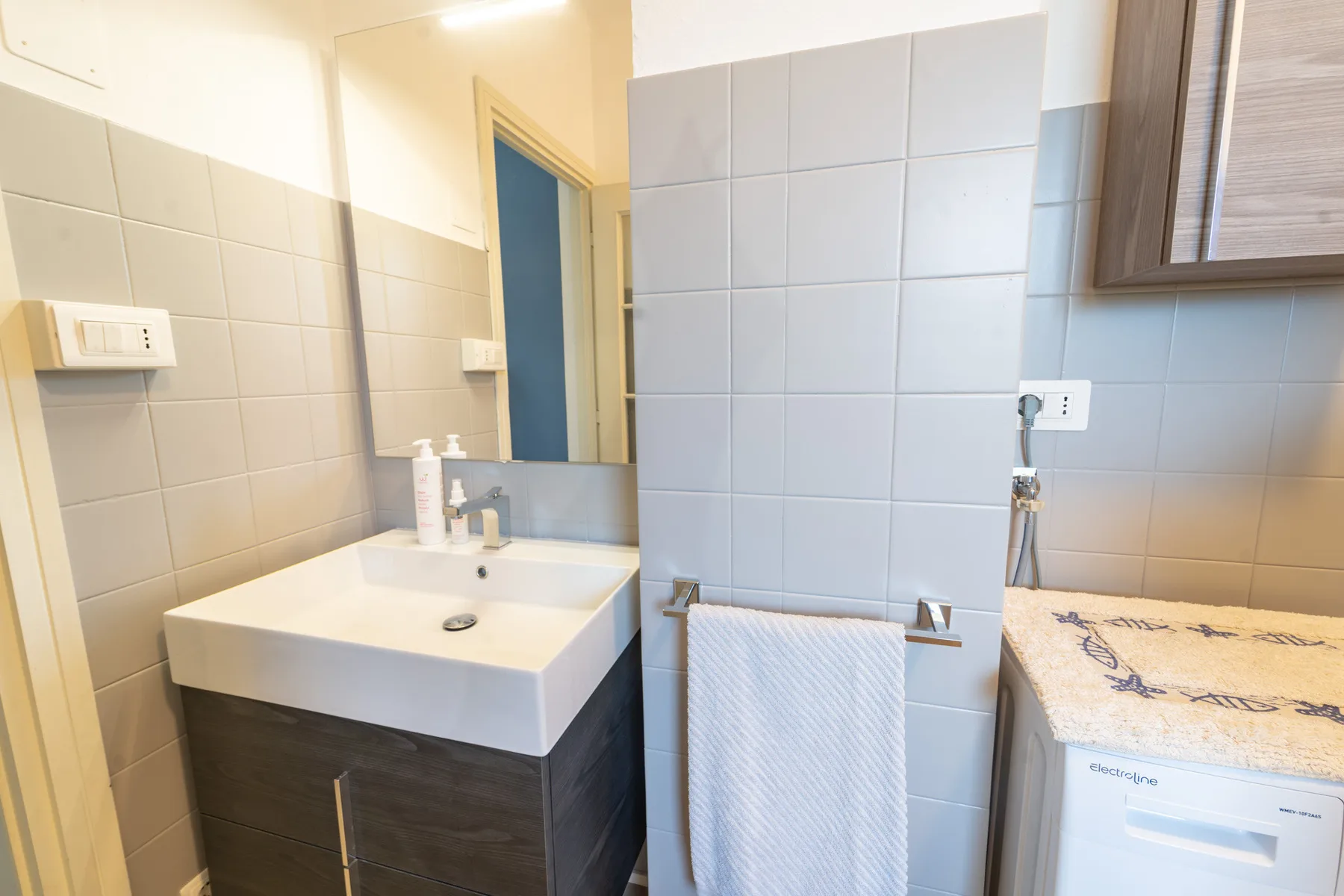 A tiled bathroom with a sink and a towel hanging on a rail.