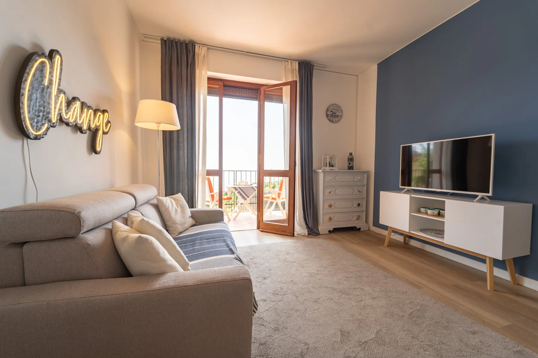 A living room with a sectional sofa and television beside glass balcony doors.