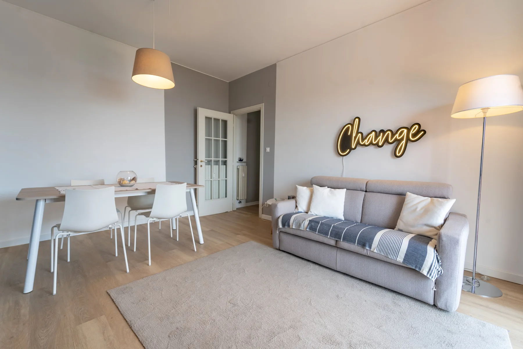 A bright living room with a dining table and seating beside a doorway.