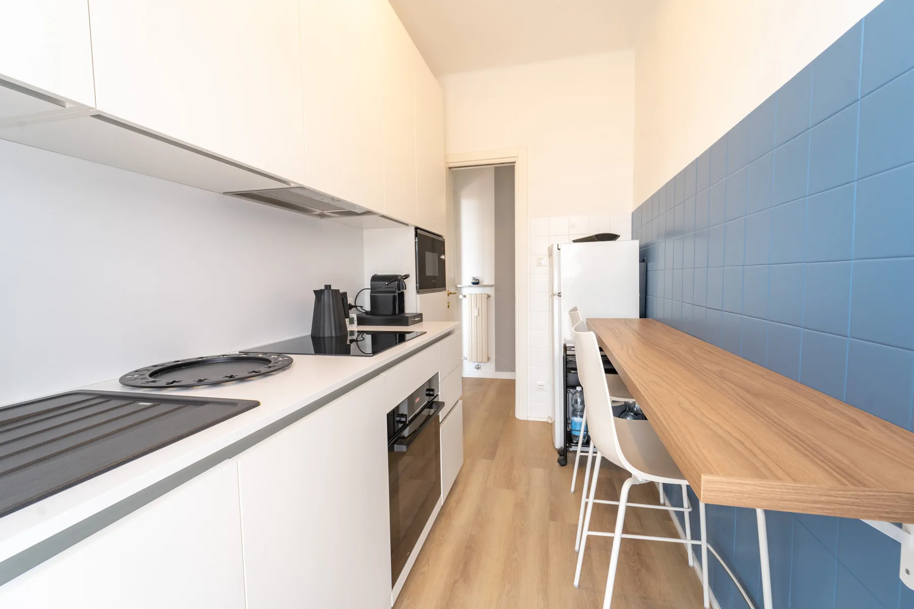 A narrow kitchen with a wood counter and blue tiled wall.