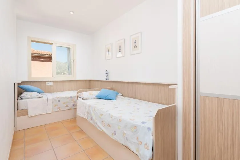 A bright bedroom with two beds and a window overlooking rooftops.