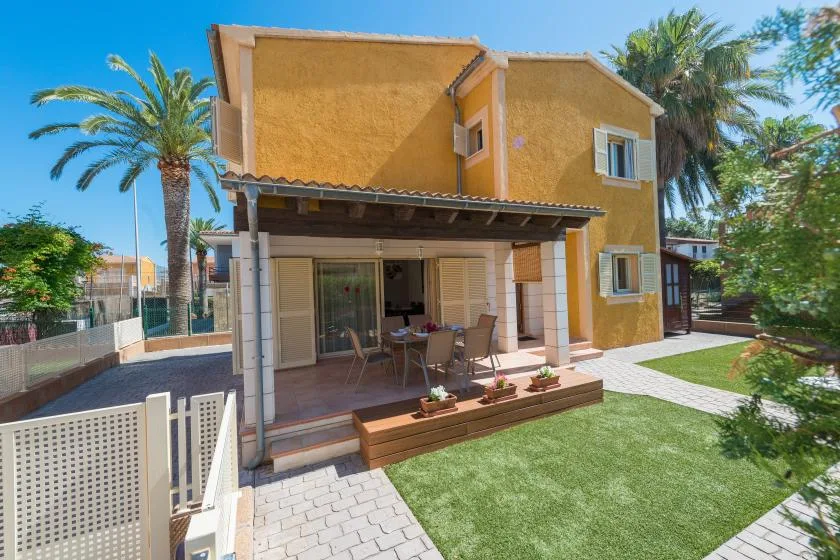 A two-story house with a covered patio opens onto a small green lawn.