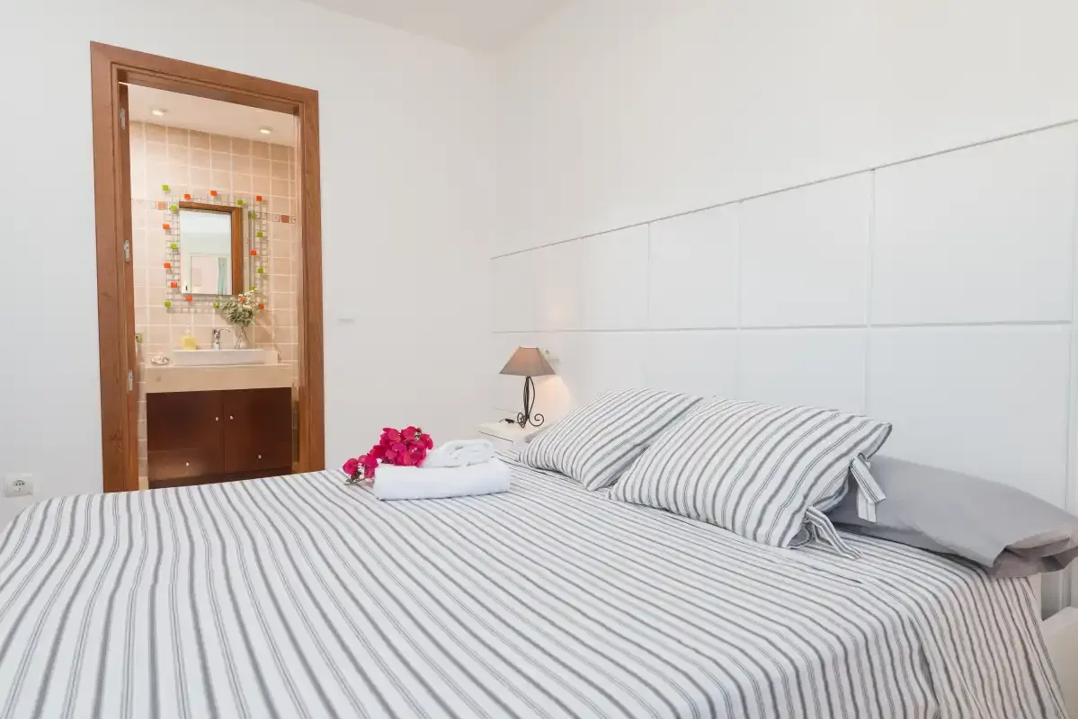 A bedroom with striped bedding and an open doorway to a bathroom.