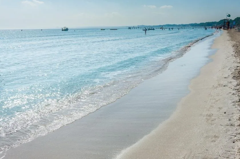 A sandy beach borders calm, shallow-looking water along the shoreline.