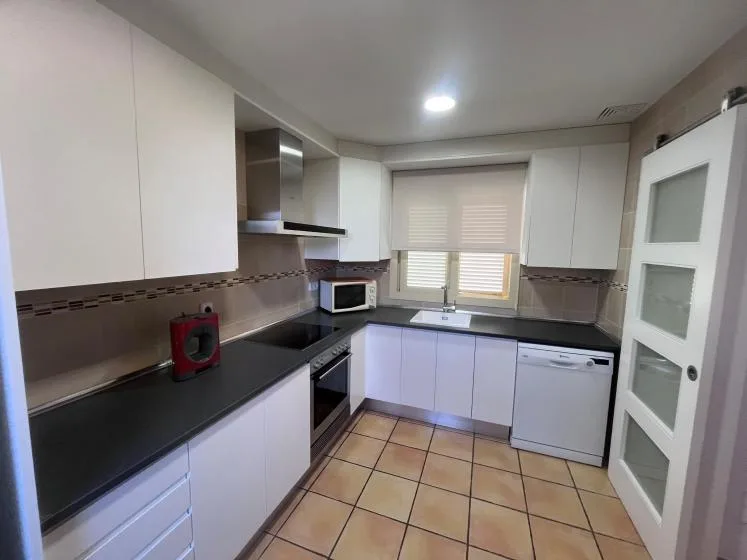 A bright kitchen with dark countertops and a window above the sink.
