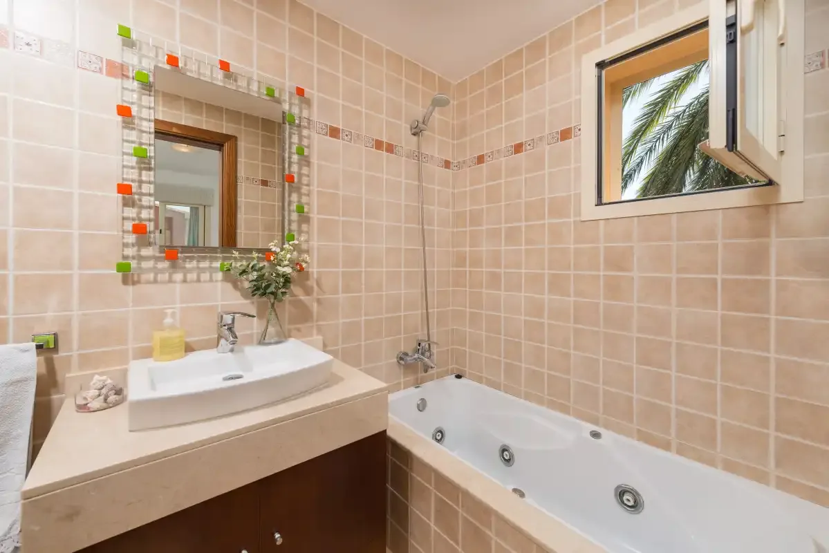 A tiled bathroom with a sink, mirror, and bathtub.