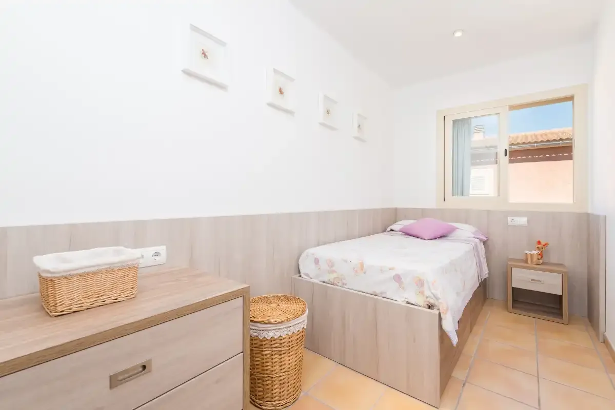 A bright bedroom with a bed, woven baskets, and a window.