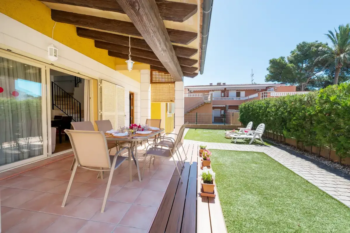 A sunny patio with outdoor seating overlooks a small lawn.