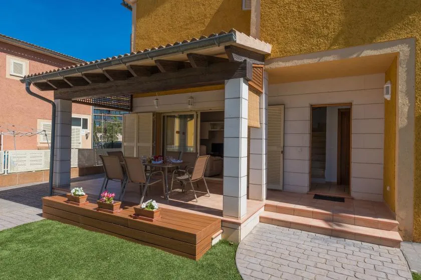 A covered patio with outdoor seating and a paved walkway beside the building.