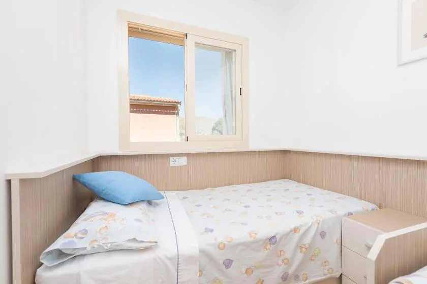 A bright bedroom with a bed beneath a window.