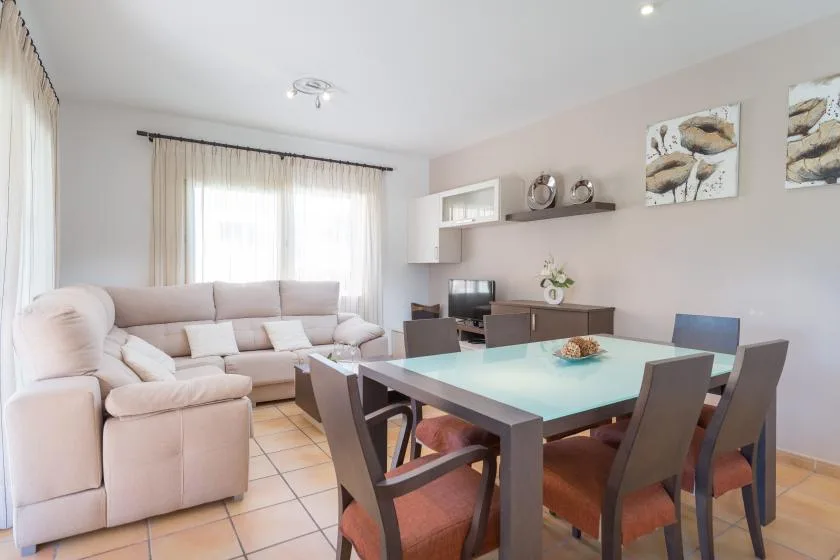 A bright living and dining room with a pale sofa and a large dining table.