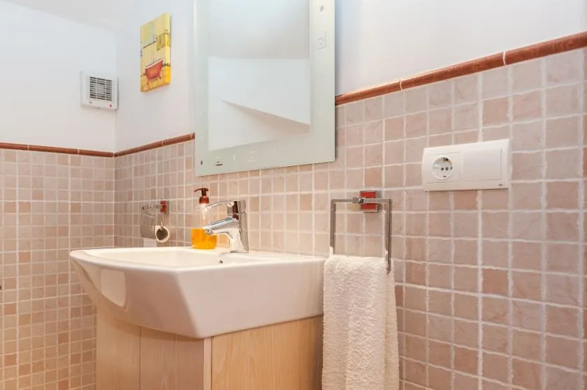 A bathroom with a wall-mounted sink and a towel hanging beside it.