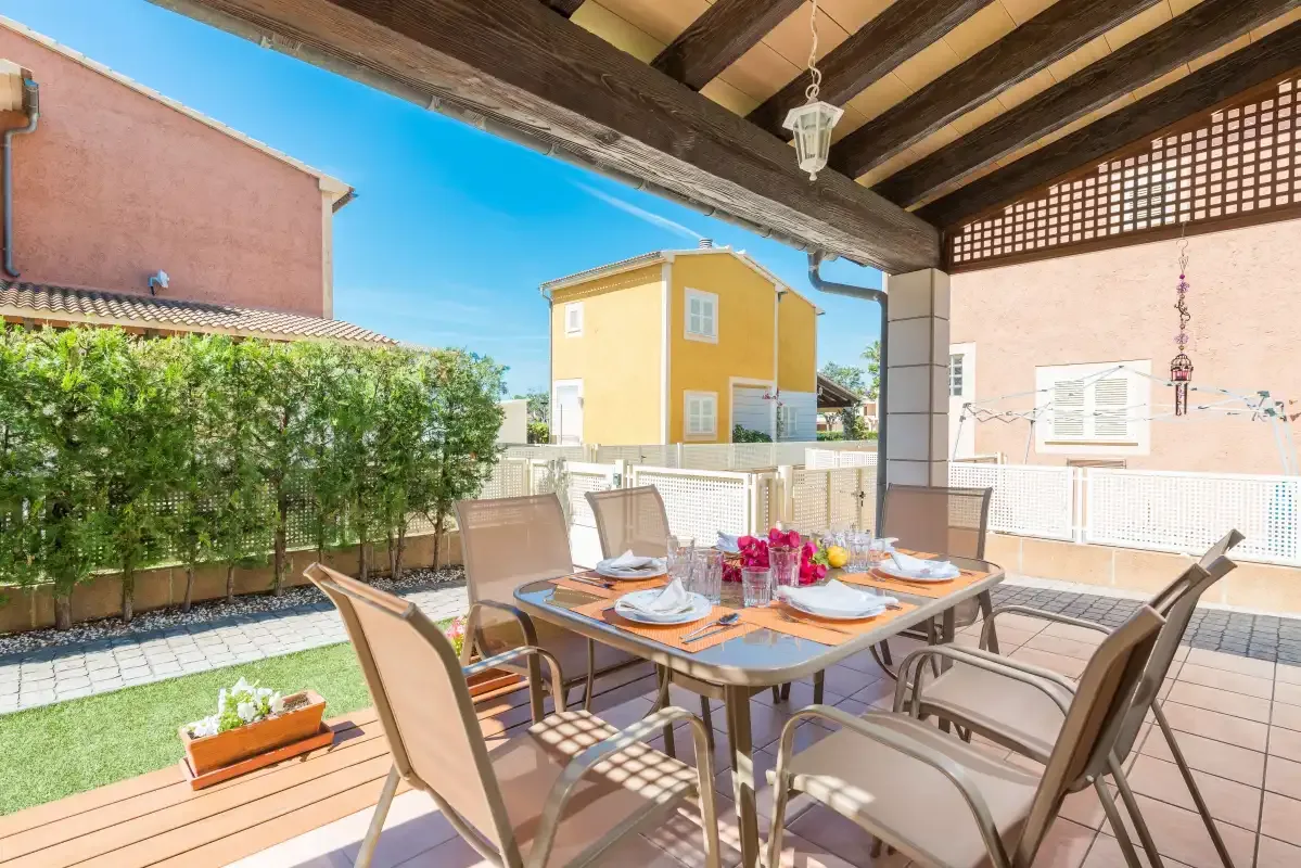 An outdoor dining area with a table and seating beneath a covered patio.