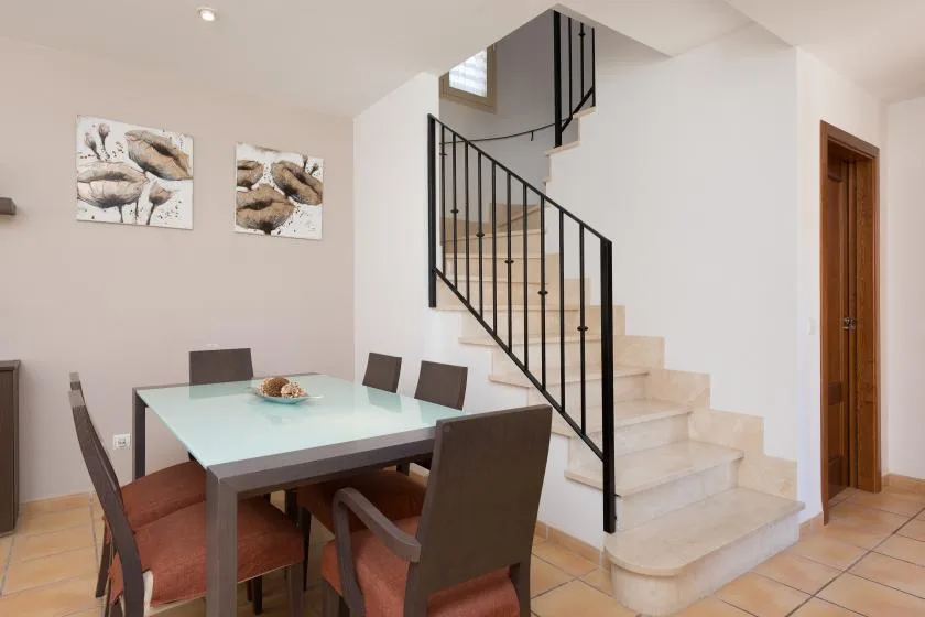 A dining area with a table and seating beside a staircase.