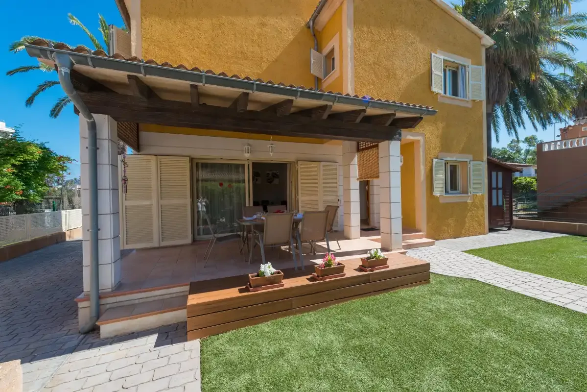 A yellow house opens onto a covered patio with outdoor seating and a lawn.