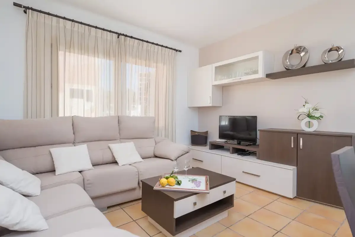 A bright living room with a sectional seating area and television.