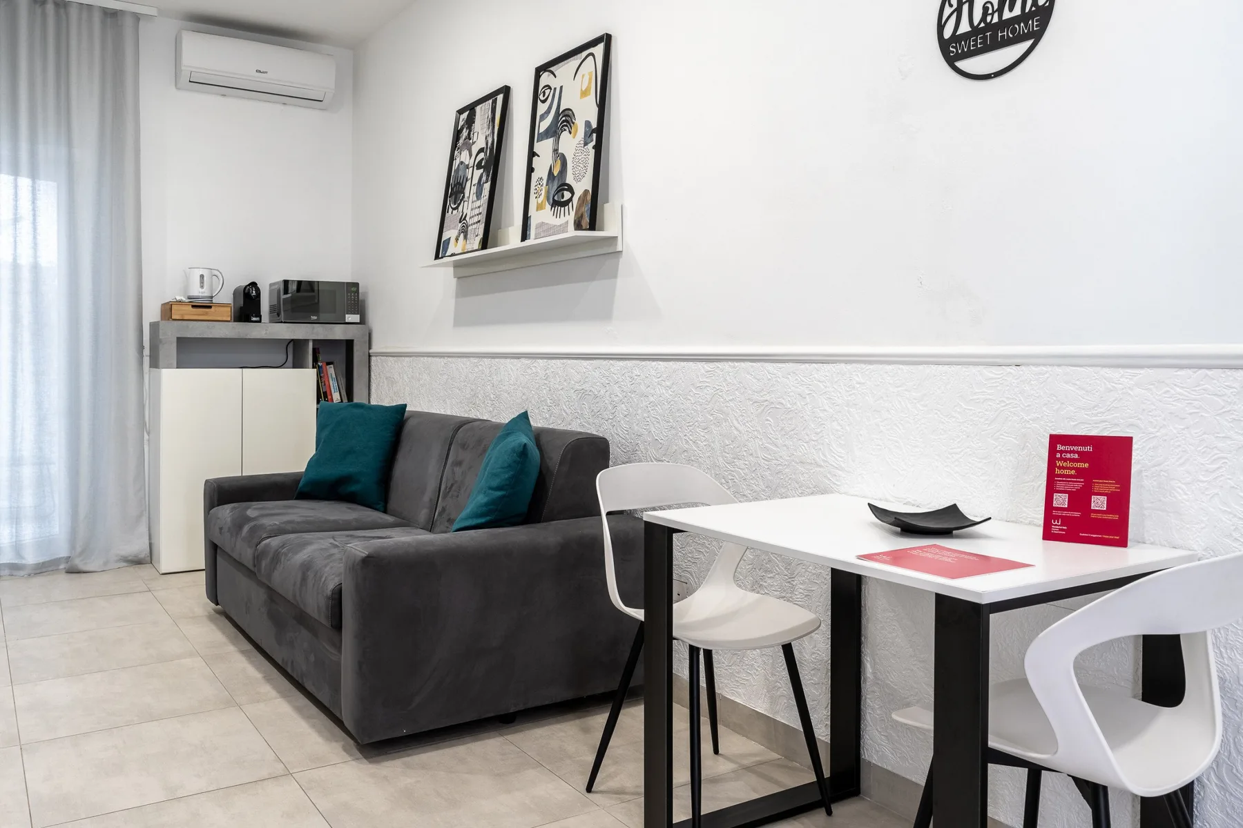 A living and dining area with a gray sofa and a white table.