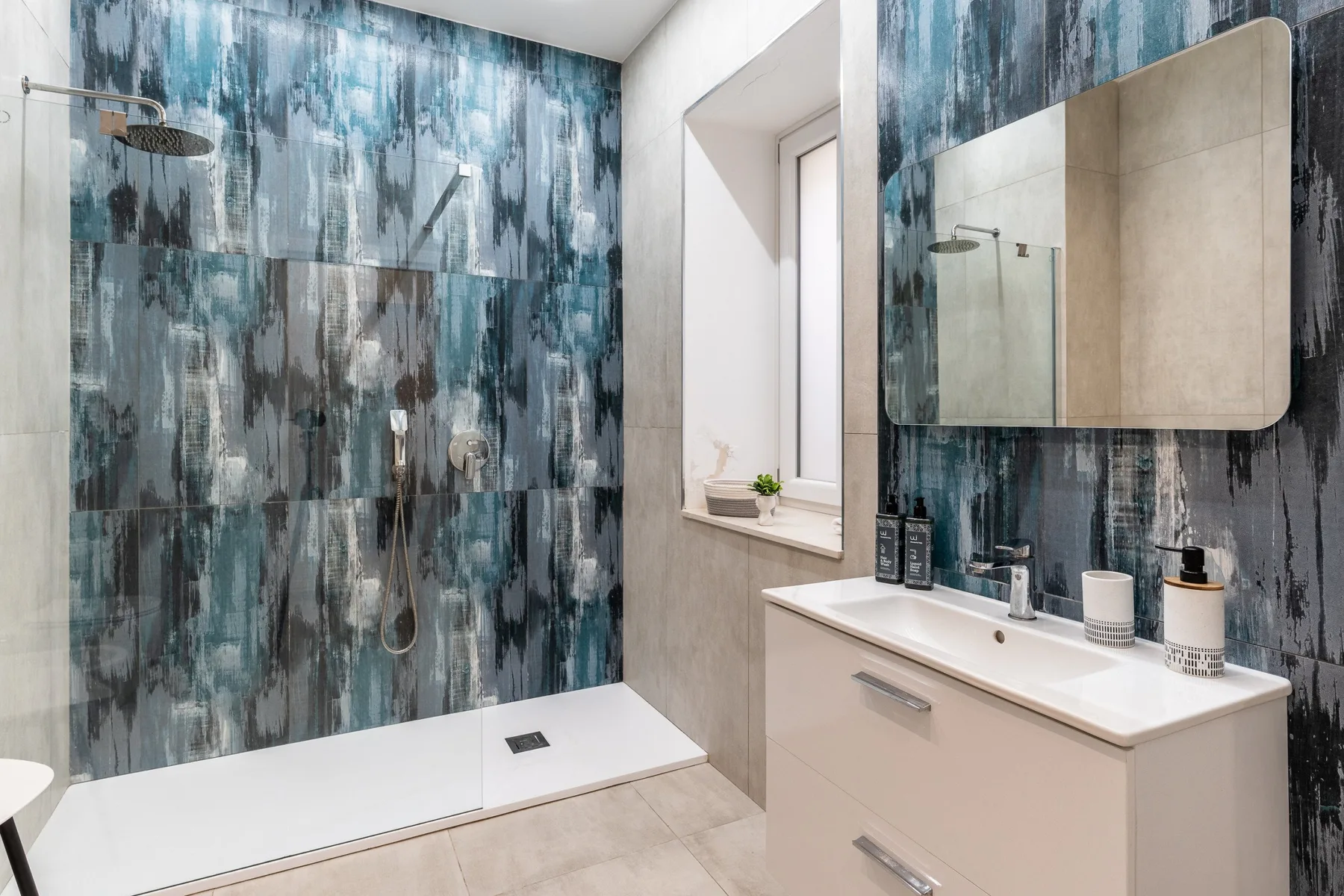 A modern bathroom with a walk-in shower and a sink beneath a mirror.