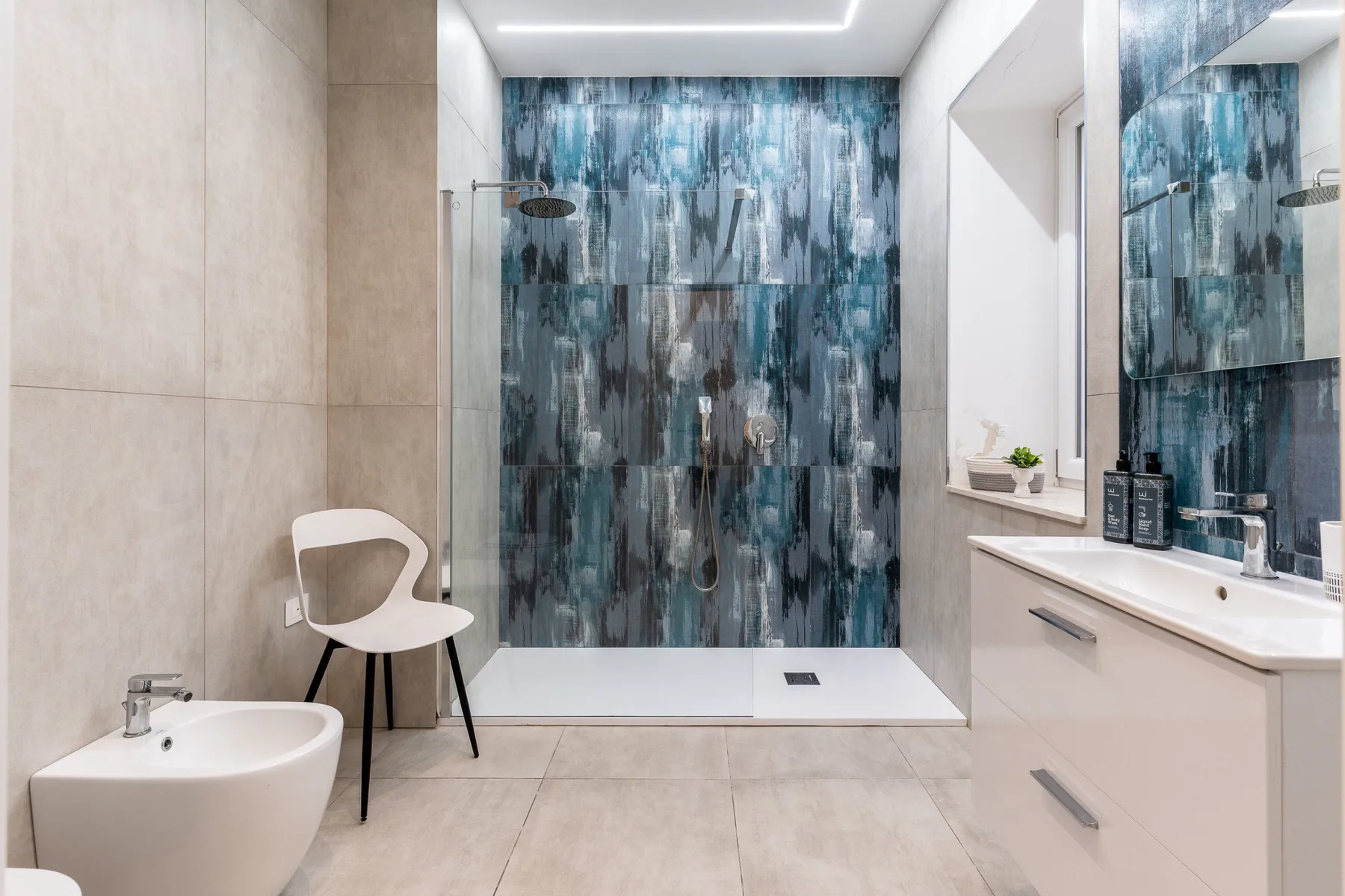 A modern bathroom with a walk-in shower and a white vanity.