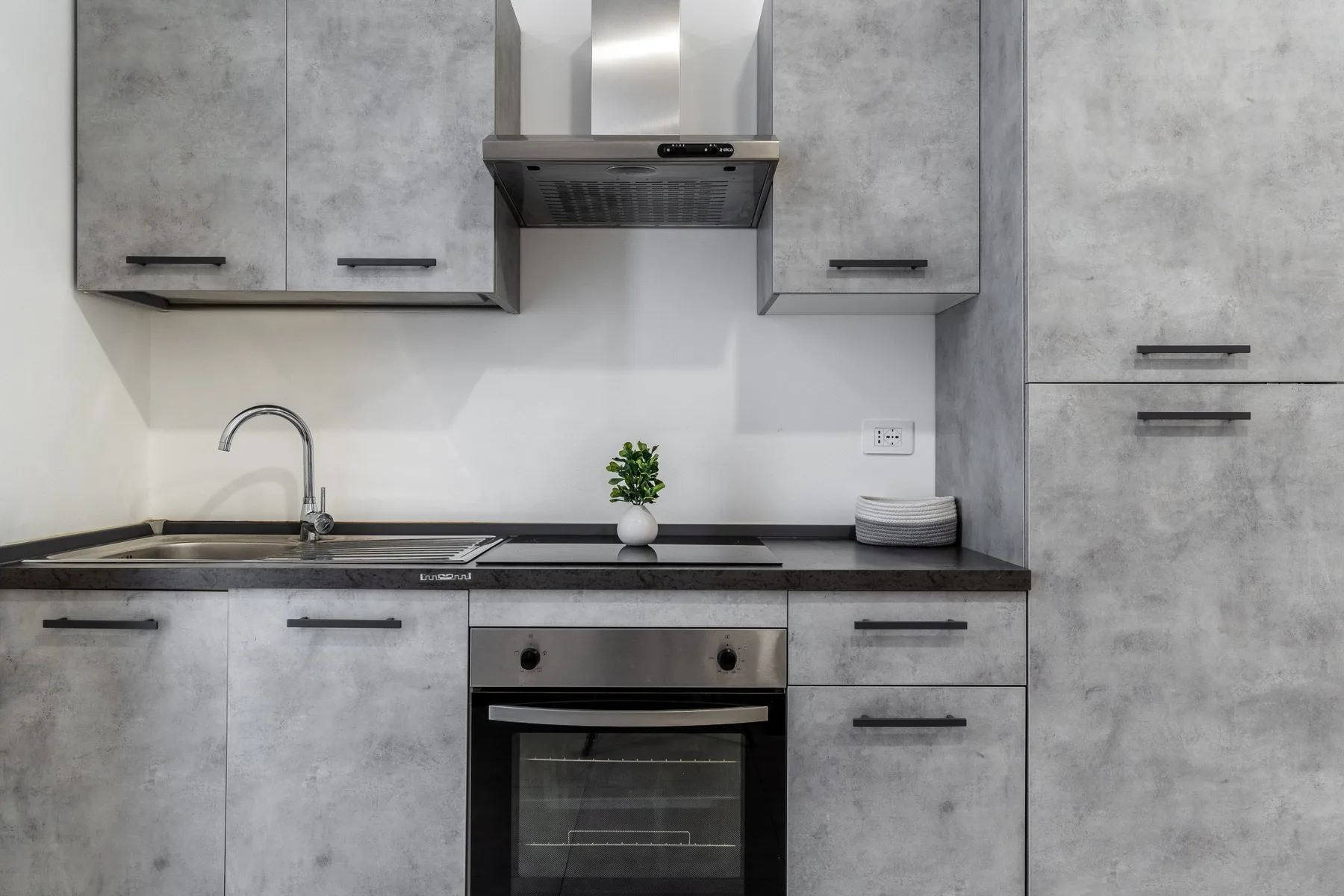 Una cocina moderna con gabinetes grises, una encimera y un horno integrado.