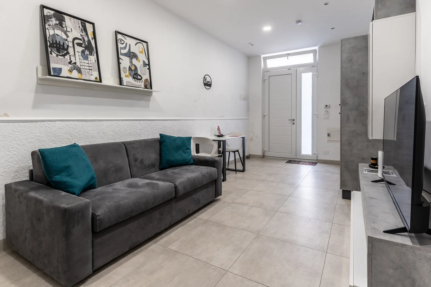 A bright living room with a gray sofa and a television.